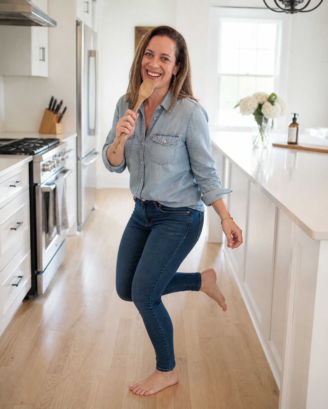Danielle smiling and dancing in her kitchen, holding a wooden spoon like a microphone